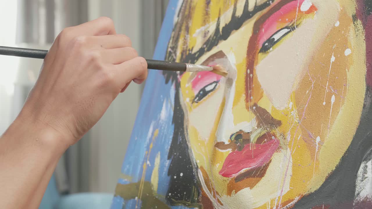 vista lateral cercana de un artista asiático que sostiene un pincel de colores mixtos y pinta la cara de una chica en el lienzo