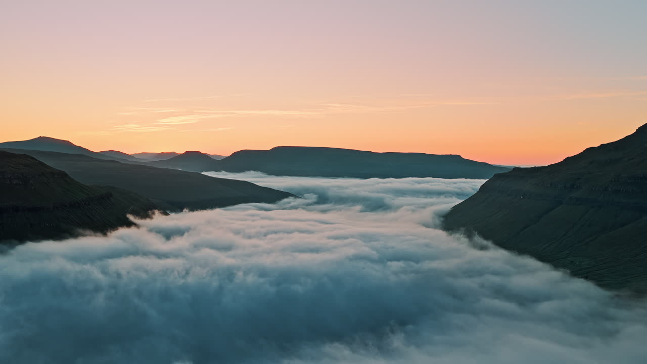 Panoramic view of mountains above a cloud-filled valley at sunrise or sunset