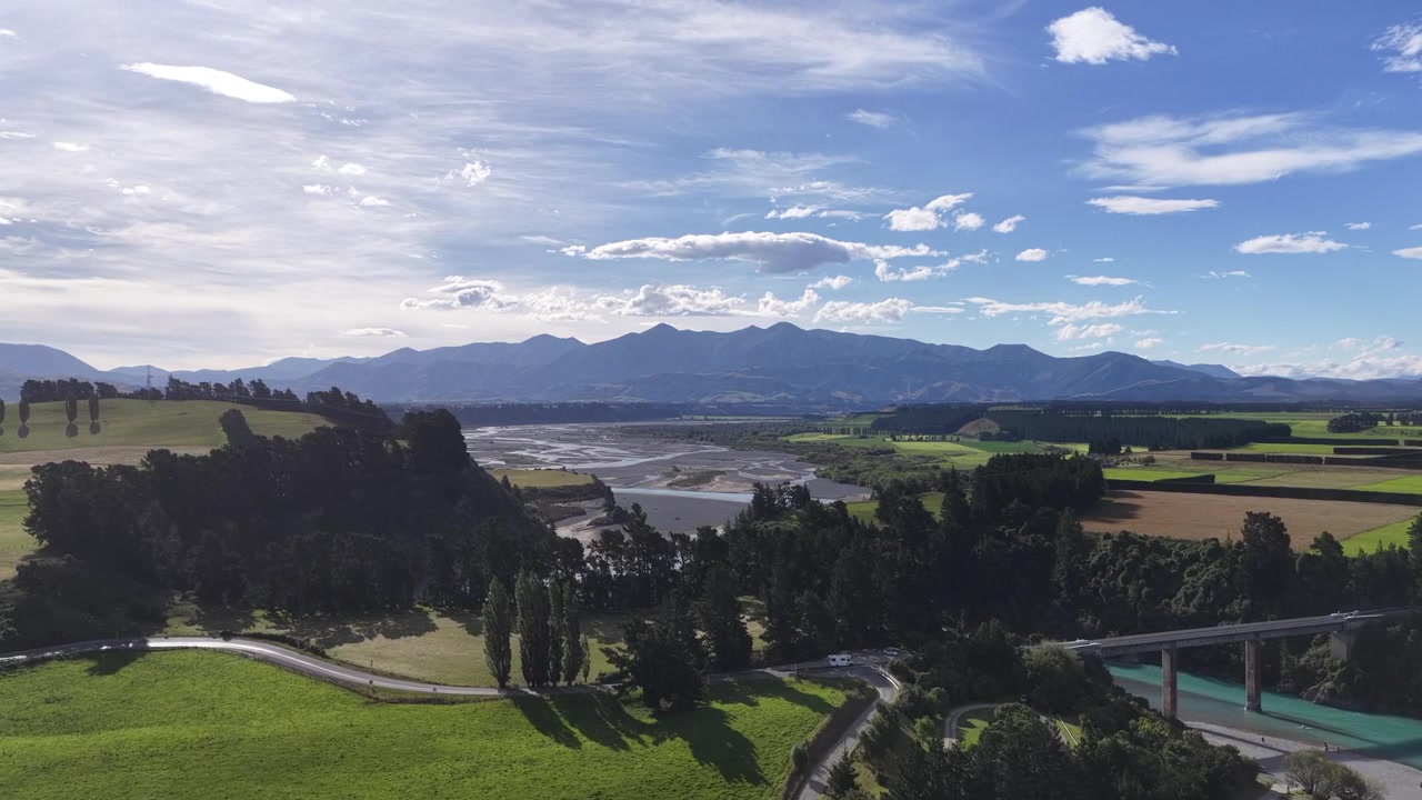 I prati e la piscina della tenuta dominano la pianura alluvionale con fiume a canali intrecciati e le montagne in lontananza, nell'Isola del Nord della Nuova Zelanda.