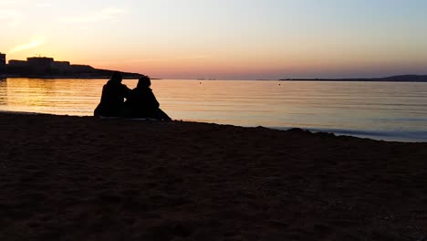 pareja viendo la puesta de sol en la playa