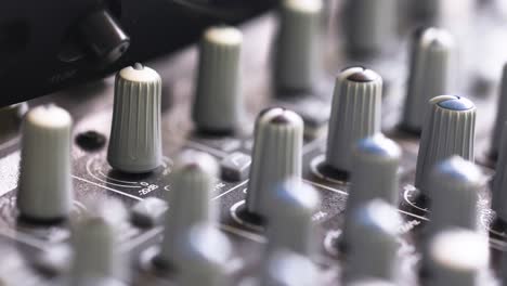 rack focus on knobs of an analog sound mixer in studio