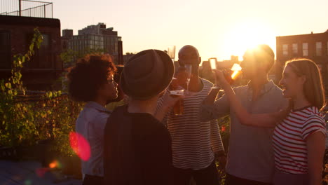 young adult friends making a toast on a rooftop at sundown