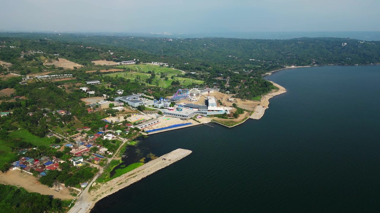 Lenta rivelazione aerea in avanti di edifici di un resort di lusso accanto al Lago Taal con acque calme e uno sfondo montuoso durante il giorno a Taunan, Batangas, Filippine.