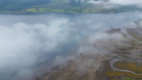 Aerial-tilt-down-flying-through-clouds-and-revealing-coastal-landscape-of-Glen-Coe