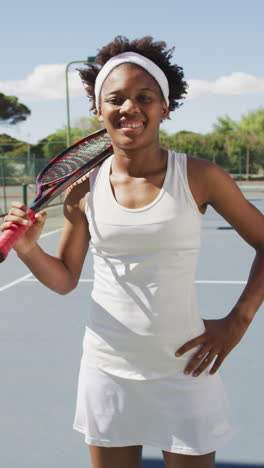 vertical video of portrait of happy african american female tennis player with tennis racket