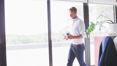 Professional-businessman-with-coffee-cup-and-digital-tablet-walking-in-modern-office-in-slow-motion