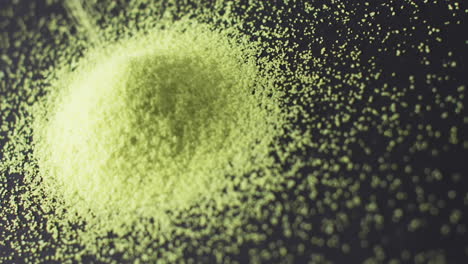 video of close up of green sand grains pouring into heap and copy space on black background