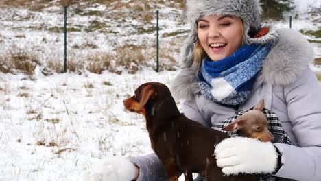 mujer jugando con sus perros pequeños fuera del invierno