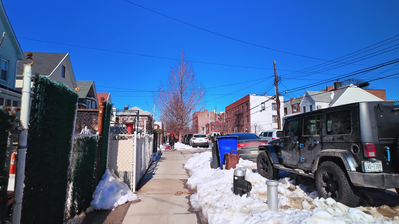 New York, USA, 9 February 2026: Sidewalk view with stacked cardboard boxes and snow in residential area