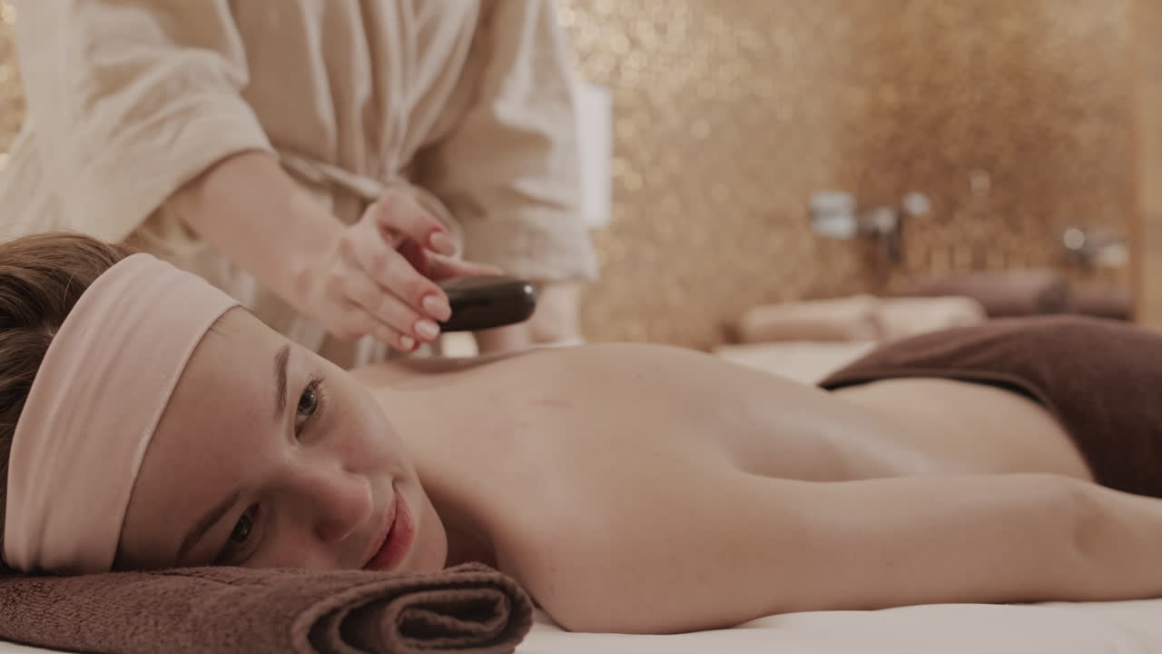 mujer recibiendo un masaje con piedras calientes