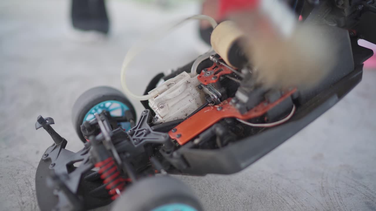 limpiando el polvo y la suciedad que hay dentro de un coche a control remoto con una pequeña escoba después de una larga carrera