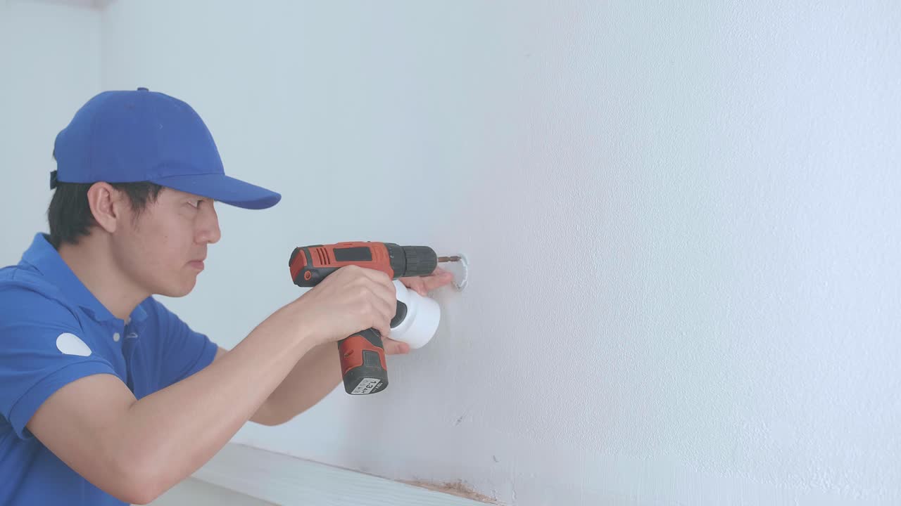 Asian Man Technician Worker Use Electric Drill And Install Cctv Camera On Wall For Security