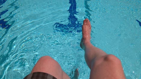 Men's-feet-on-the-background-of-the-swimming-pool,-relax-on-vacation