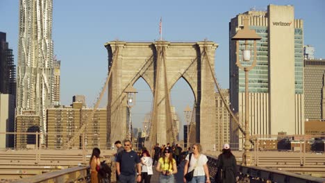 commuters crossing brooklyn bridge in new york on a sunny evening