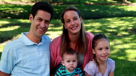 Young-family-smiling-at-the-camera-in-the-park