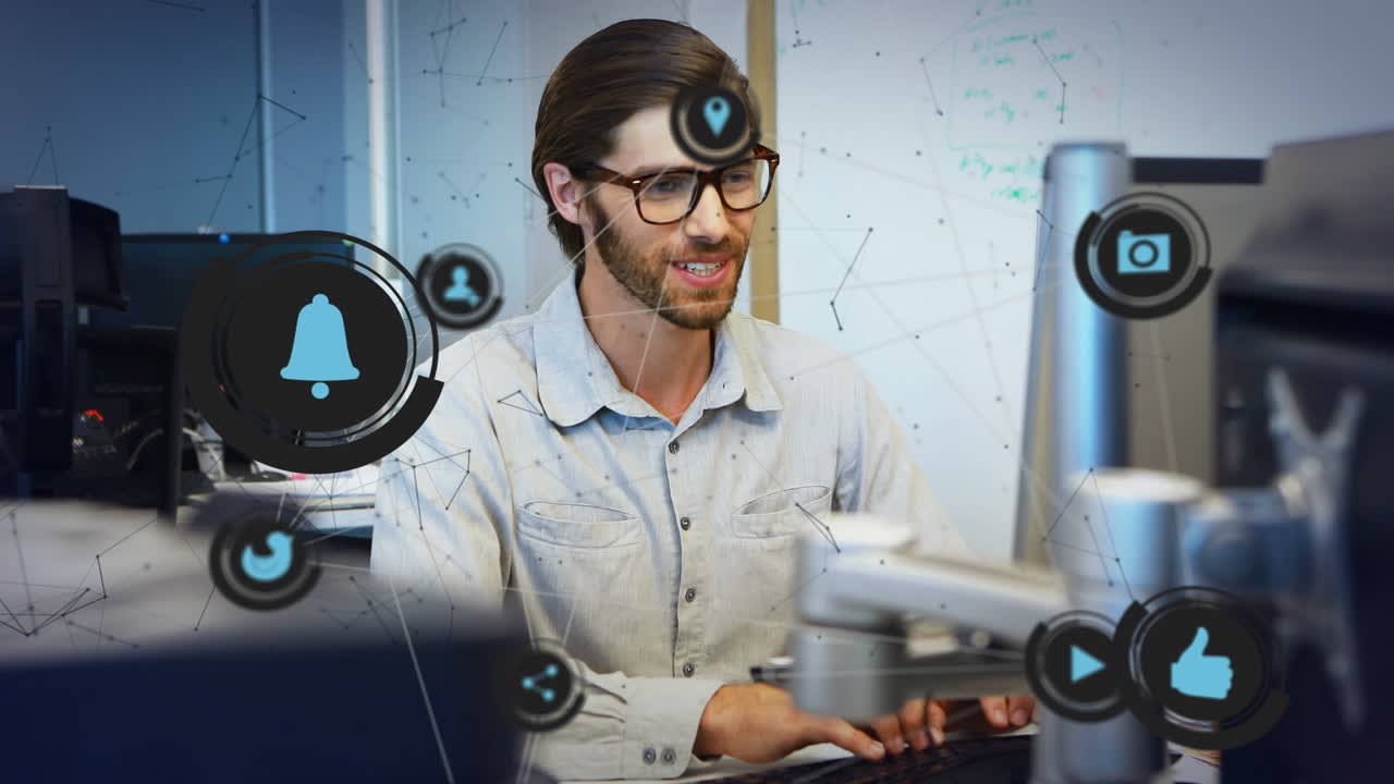 animación de formas e iconos de medios sobre un hombre de negocios caucásico que usa computadora en la oficina