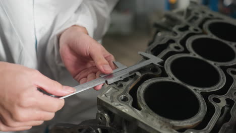 close up hand view of technician using vernier caliper to measure car engine dimensions in automotive workshop, measurement process for mechanical accuracy in engineering workspace