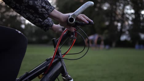 female hands on bicycle in the park medium shot slow tilting shot