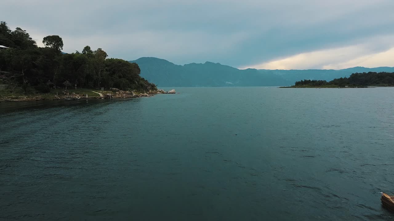 Drone aerial flying over a man paddling on a boat in beautiful Lake Atitlan, Guatemala
