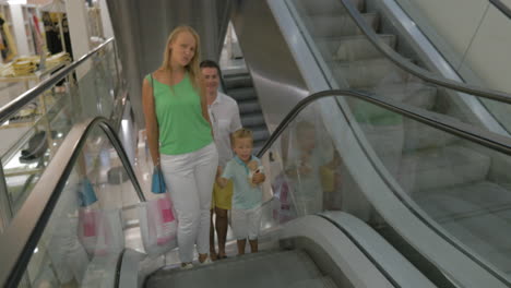 familia sonriente en la escalera mecánica después de las compras