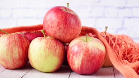 manzanas rojas frescas en una bolsa de malla naranja