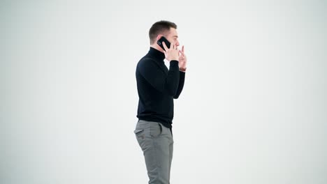 young businessman talking on the phone. handsome man in black sweater and grey trousers leading e-business through the cellphone. man isolated on white.