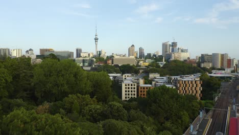 amazing auckland skyline revealed behind green trees, train station