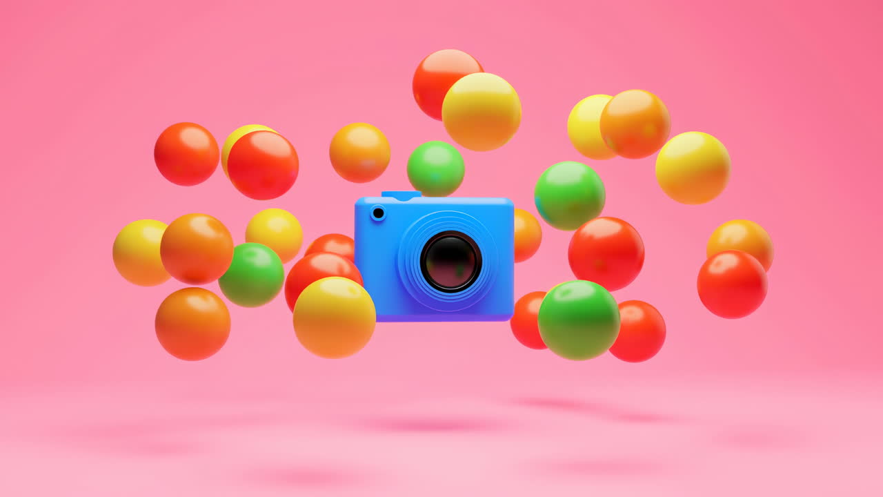 Macchina fotografica giocattolo blu circondata da sfere colorate fluttuanti su sfondo rosa