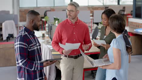 team of diverse colleagues discussing together while standing at office