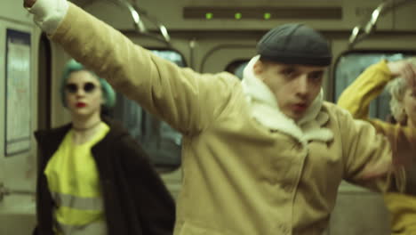 hombre joven vestido a la moda bailando con chicas en el vagón del metro