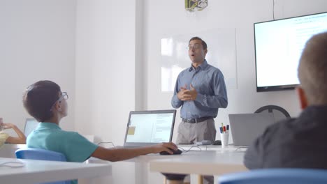 maestro masculino y estudiantes de escuela discutiendo la lección