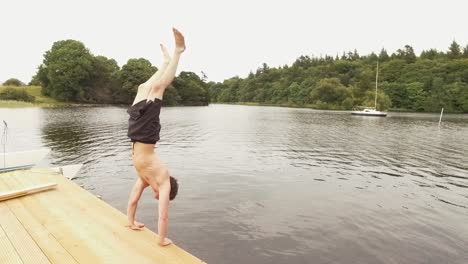 young man performs handstand dive off the jetty into river