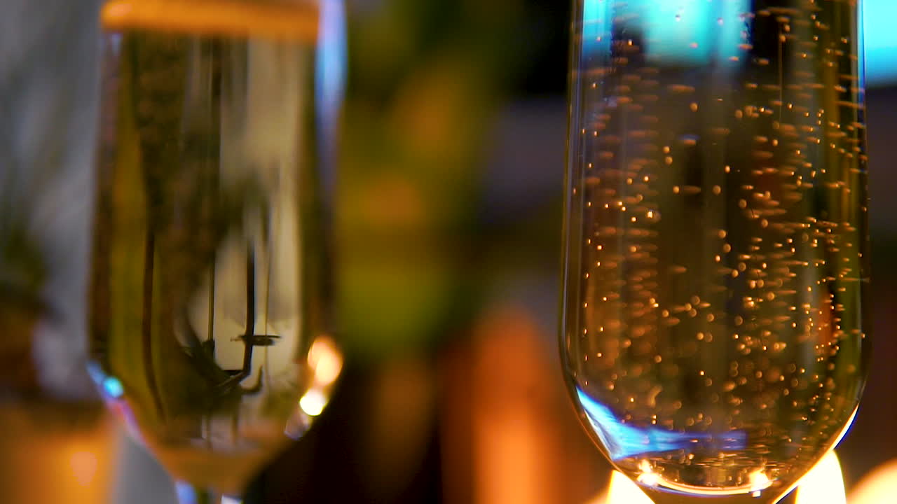 Primissimo piano di champagne in un bicchiere su sfondo chiaro, il bicchiere presenta molta schiuma e bollicine