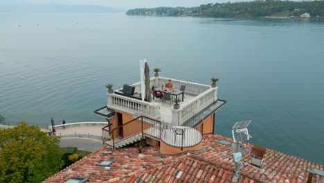 stunning terrace on top of cottage building in front of calm lake landscape