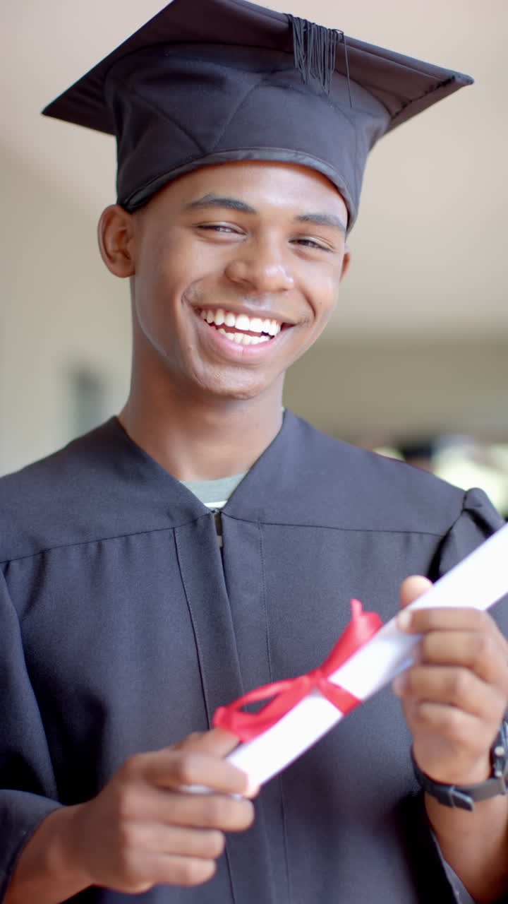 Vertical video: Graduating from school, teenager smiling and holding diploma in cap and gown