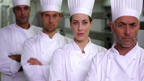 four stern chefs looking at camera with arms crossed