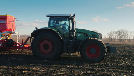 toma panorámica de steadicam: tractores con sembradoras siembran trigo en el campo a principios de la primavera 1