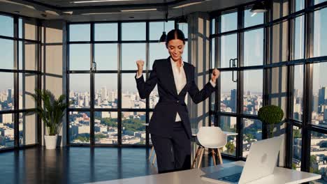 A woman in a suit celebrates in a modern office with city views