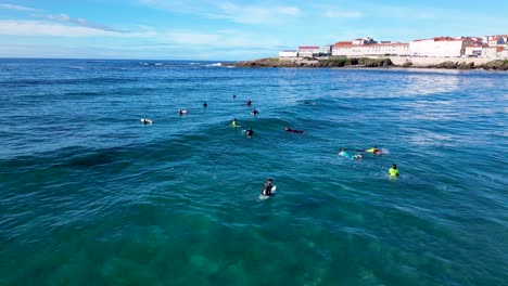 aerial view of surfers swimming and sitting on their surfboards in the ocean in caion beach, laracha, spain