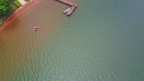 Overhead-Aerial-Drone-Shot-Following-the-Shoreline-of-a-River-in-Brasilia-Brazil-Revealing-Canoes-and-People-On-A-Dock