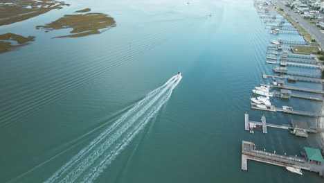 aerial tracking speedboat driving along wrightsville beach, north carolina