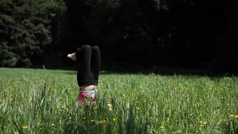 una mujer que hace yoga en un campo se cae de su soporte de cabeza