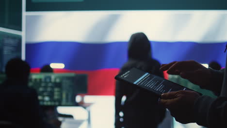 Person-uses-tablet-in-governmental-cyber-security-room-working-for-Russian-flag