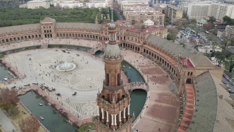 Orbitando-Sobre-La-Torre-De-La-Plaza-De-España-Revelando-La-Majestuosa-Plaza-Llena-De-Turistas,-Sevilla