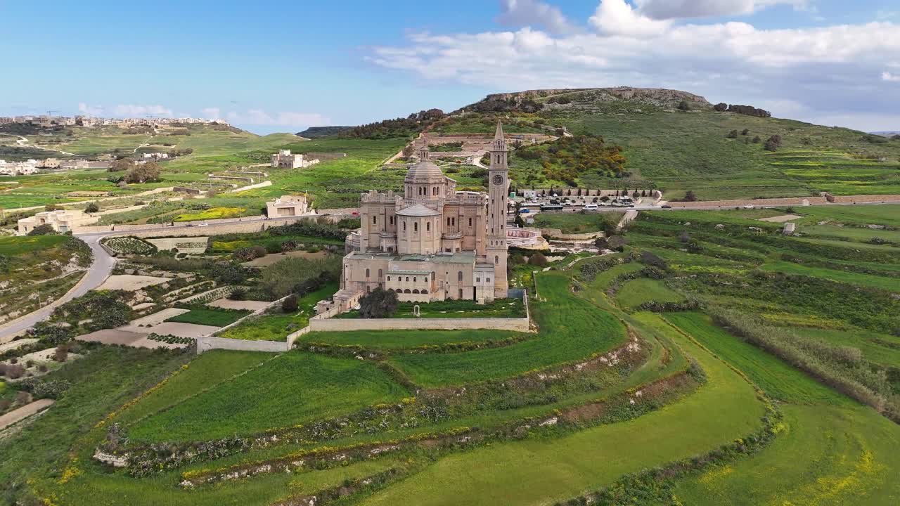 Il Santwarju Bażilika tal-Madonna ta’ Pinu a Għarb Gozo Malta si erge isolato in una campagna aperta di campi terrazzati e terreno calcareo vicino alla collina di Għammar e al paesaggio di Ta’ Għammar, con un drone in orbita.