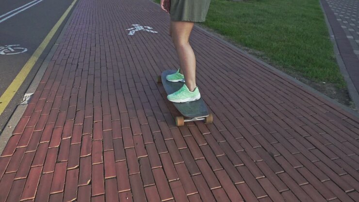 Back view young woman riding on skateboard. Slow motion skateboarding outdoors