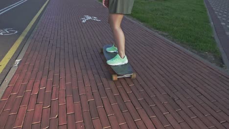 back view young woman riding on skateboard. slow motion skateboarding outdoors