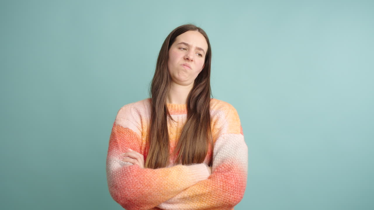 Woman expressing disgust with crossed arms on turquoise background