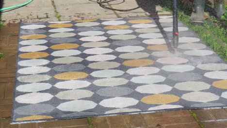 man washing carpet with pressure washer outdoors
