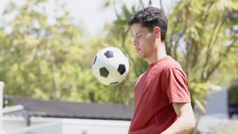 happy biracial man practicing football skills in sunny garden, copy space, slow motion